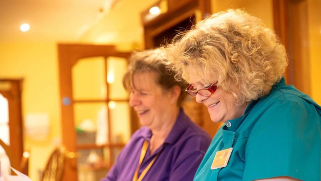 Two hospice volunteers smiling.