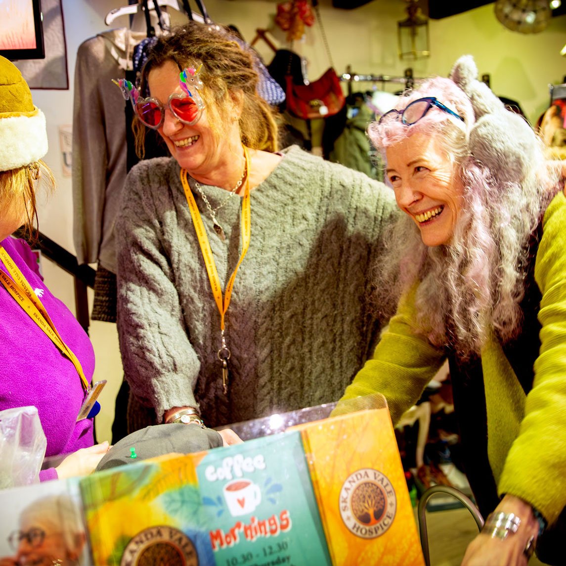 Volunteers at the Skanda Vale Hospice Charity Shop wearing novelty glasses.
